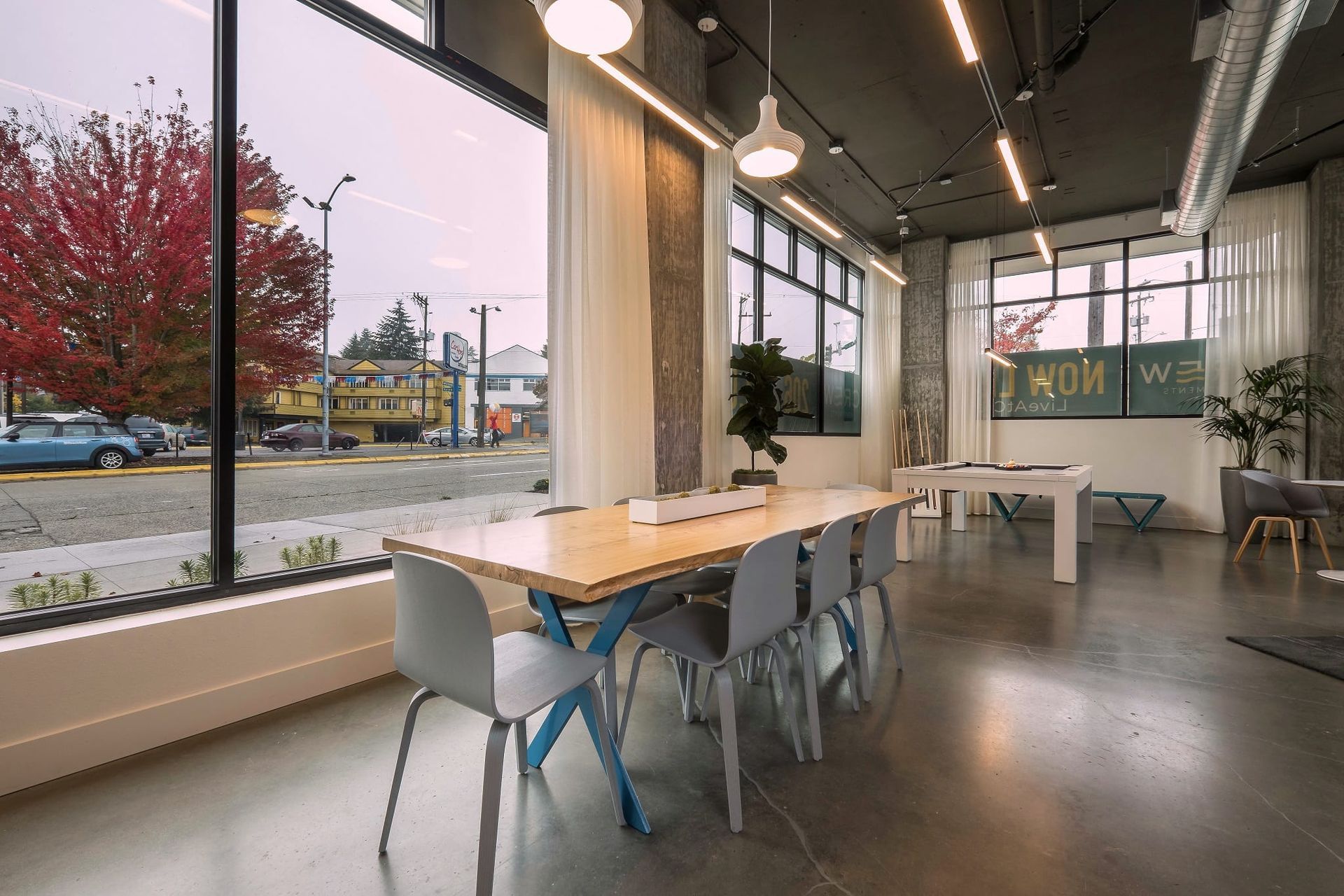 A room with a long table and chairs in front of a window at CREW Apartments in Seattle, WA.