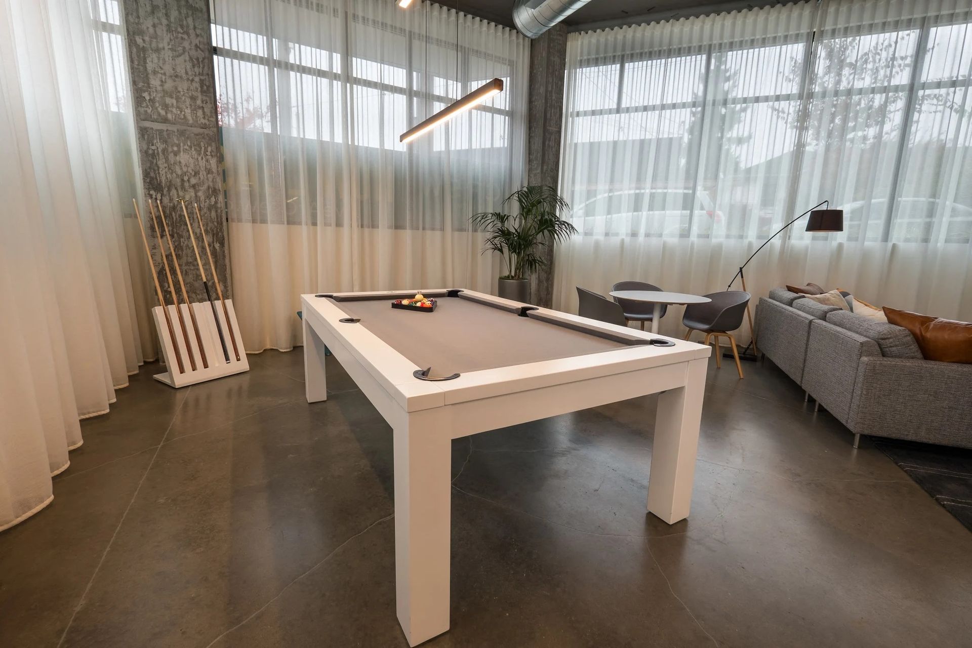 A pool table is in a living room next to a couch at CREW Apartments in Seattle, WA.