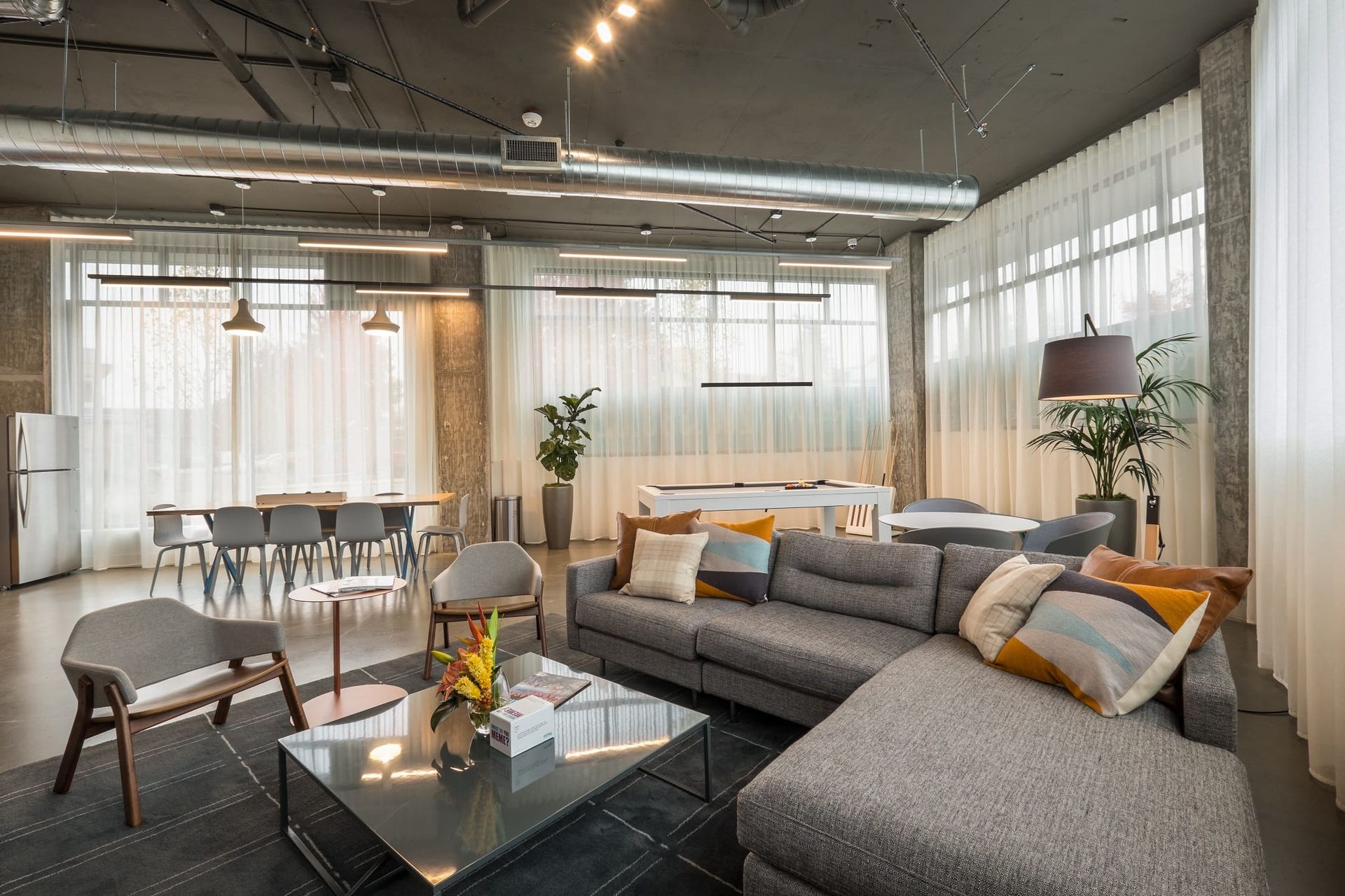 A living room with a couch , table , chairs and a pool table at CREW Apartments in Seattle, WA.