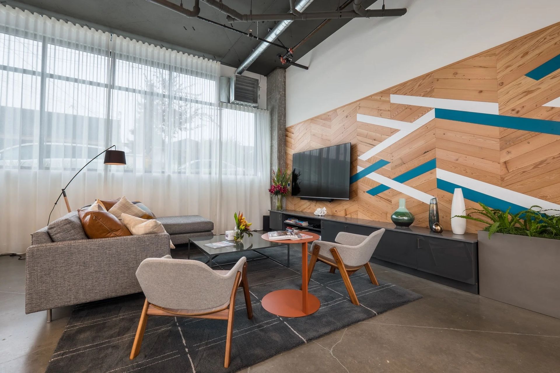 A living room with a couch , chairs , table and television at CREW Apartments in Seattle, WA.