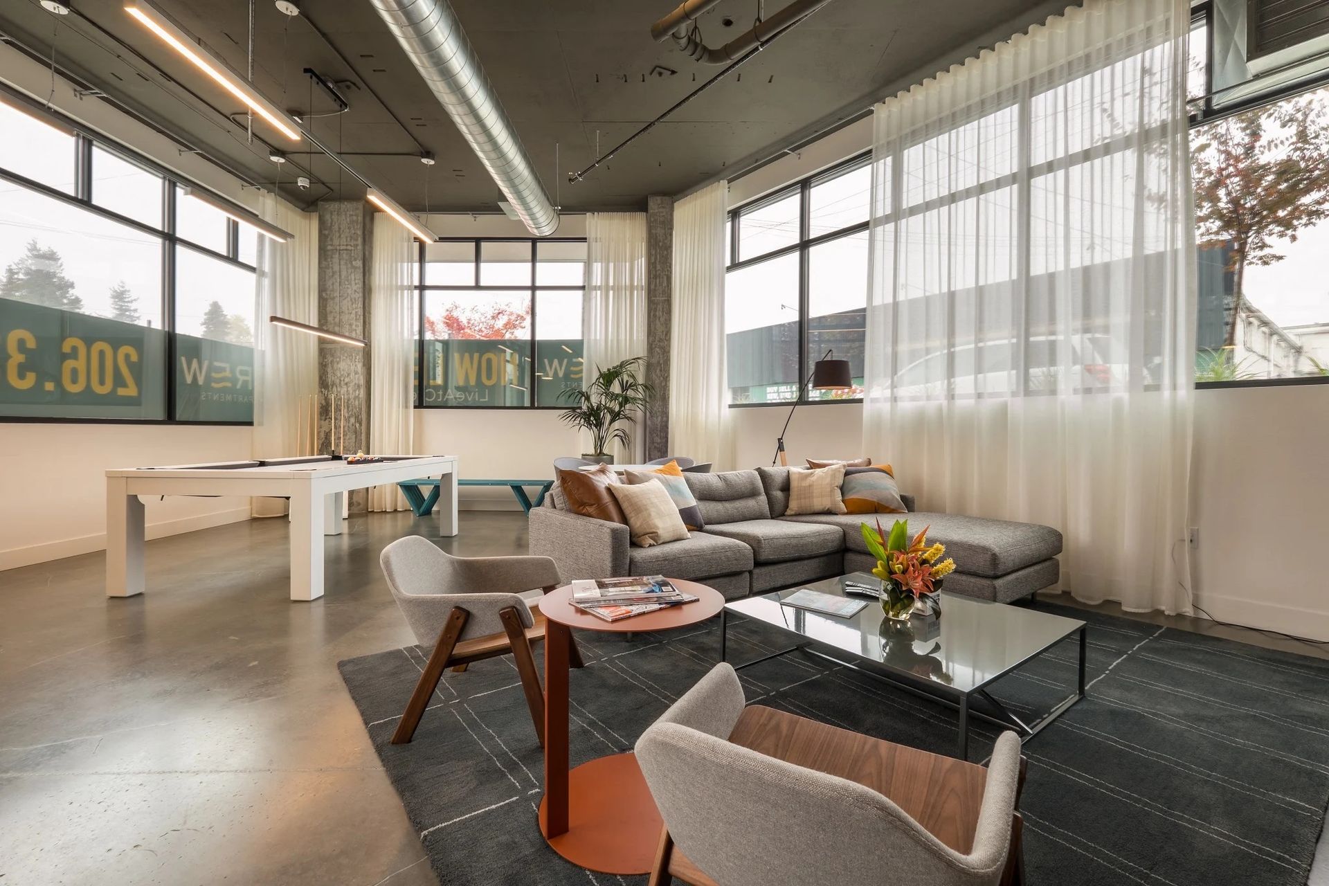 A living room filled with furniture and a pool table at CREW Apartments in Seattle, WA.