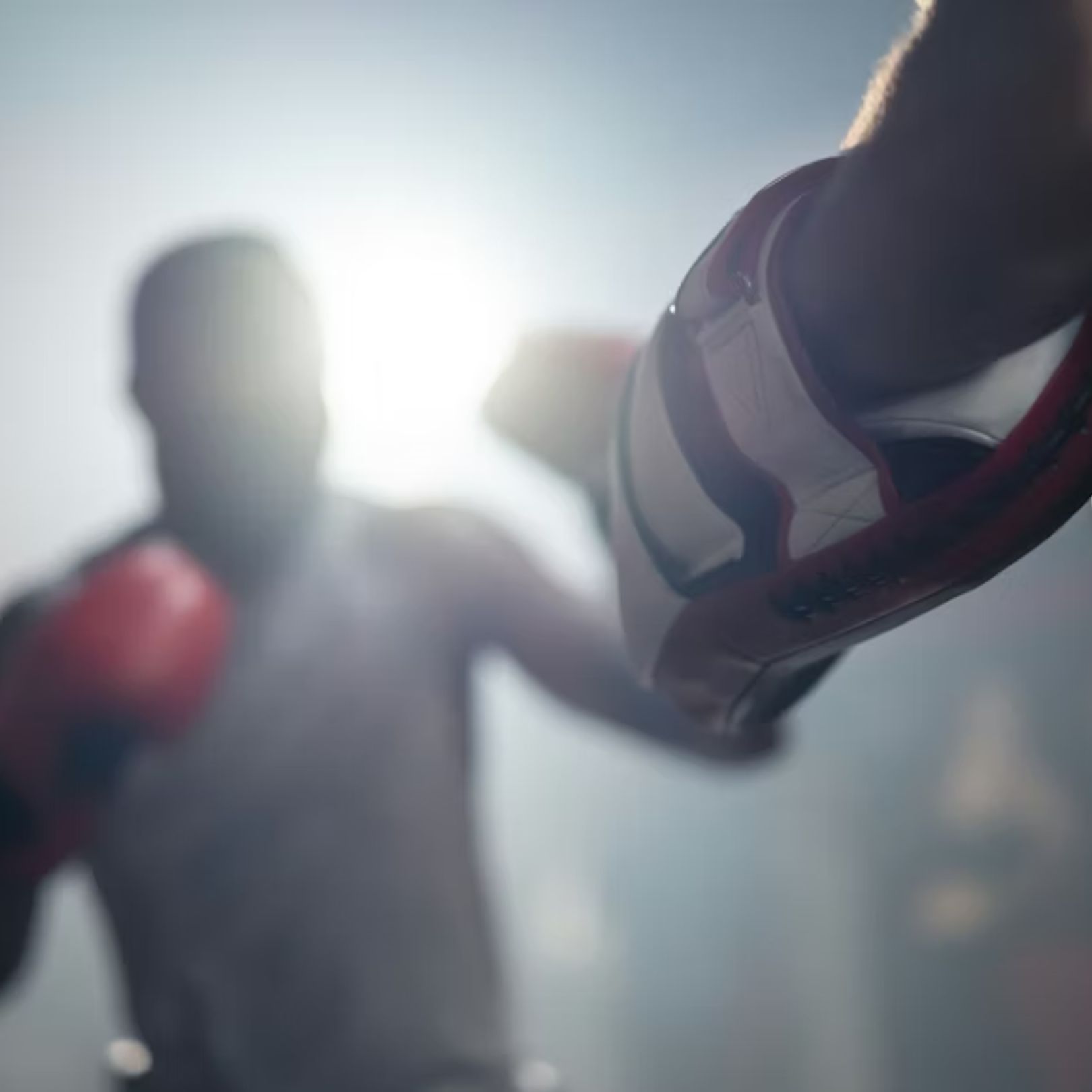 A first-person view of a boxer wearing white and red gloves sparring with a coach in a brightly lit gym.