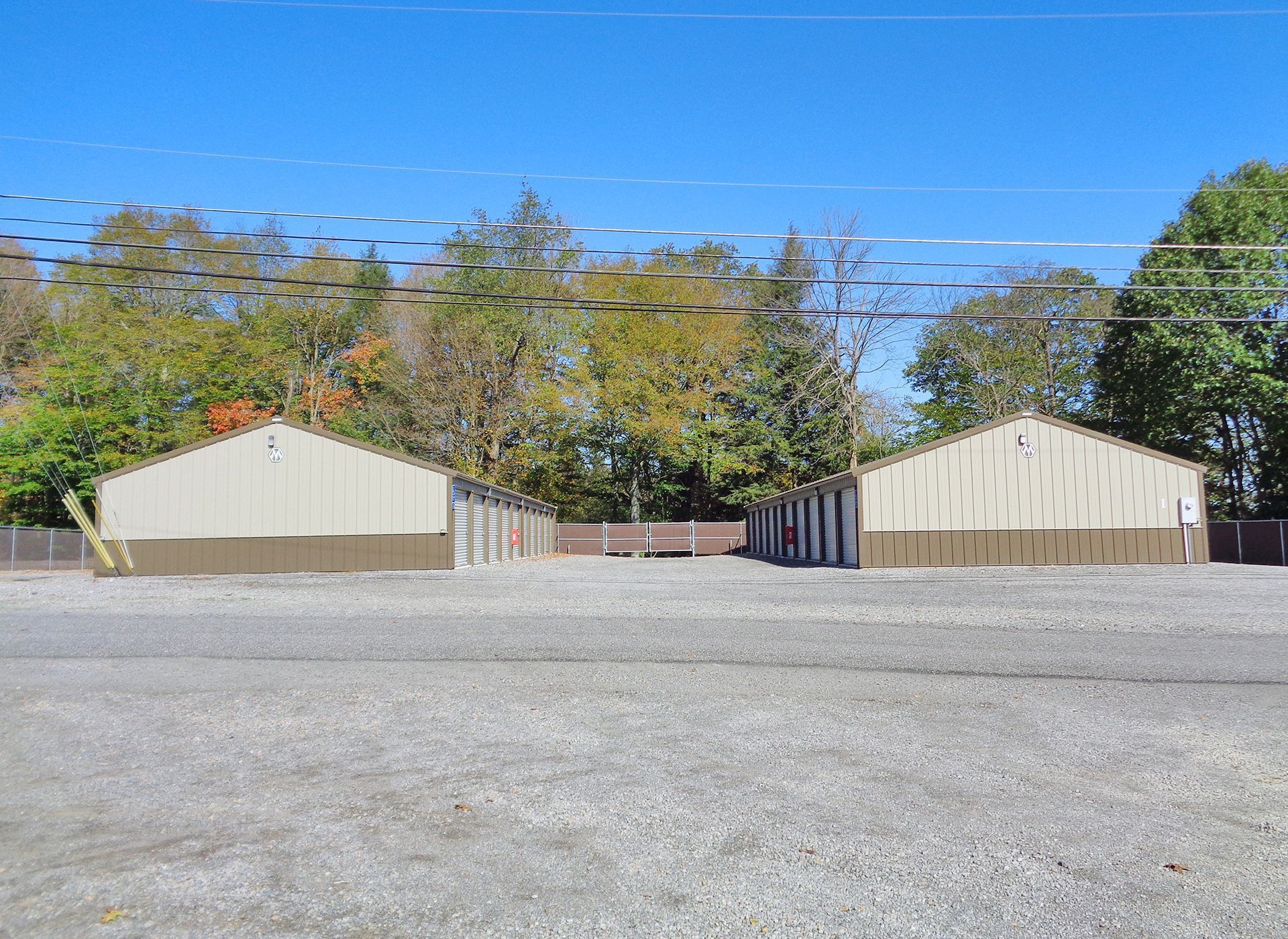 Two buildings are sitting next to each other in a gravel lot.