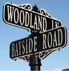 A street sign for woodland lane and bayside road.