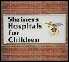 A sign for shriners hospitals for children is on a brick wall.