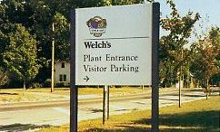 A sign that says welch 's plant entrance visitor parking on it.