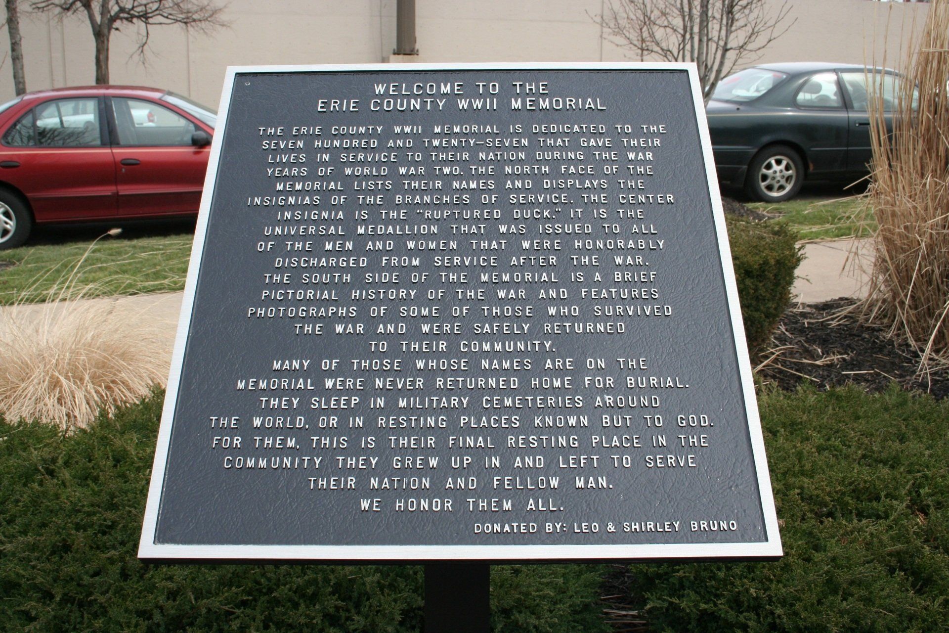 A plaque in front of a red car that says welcome to