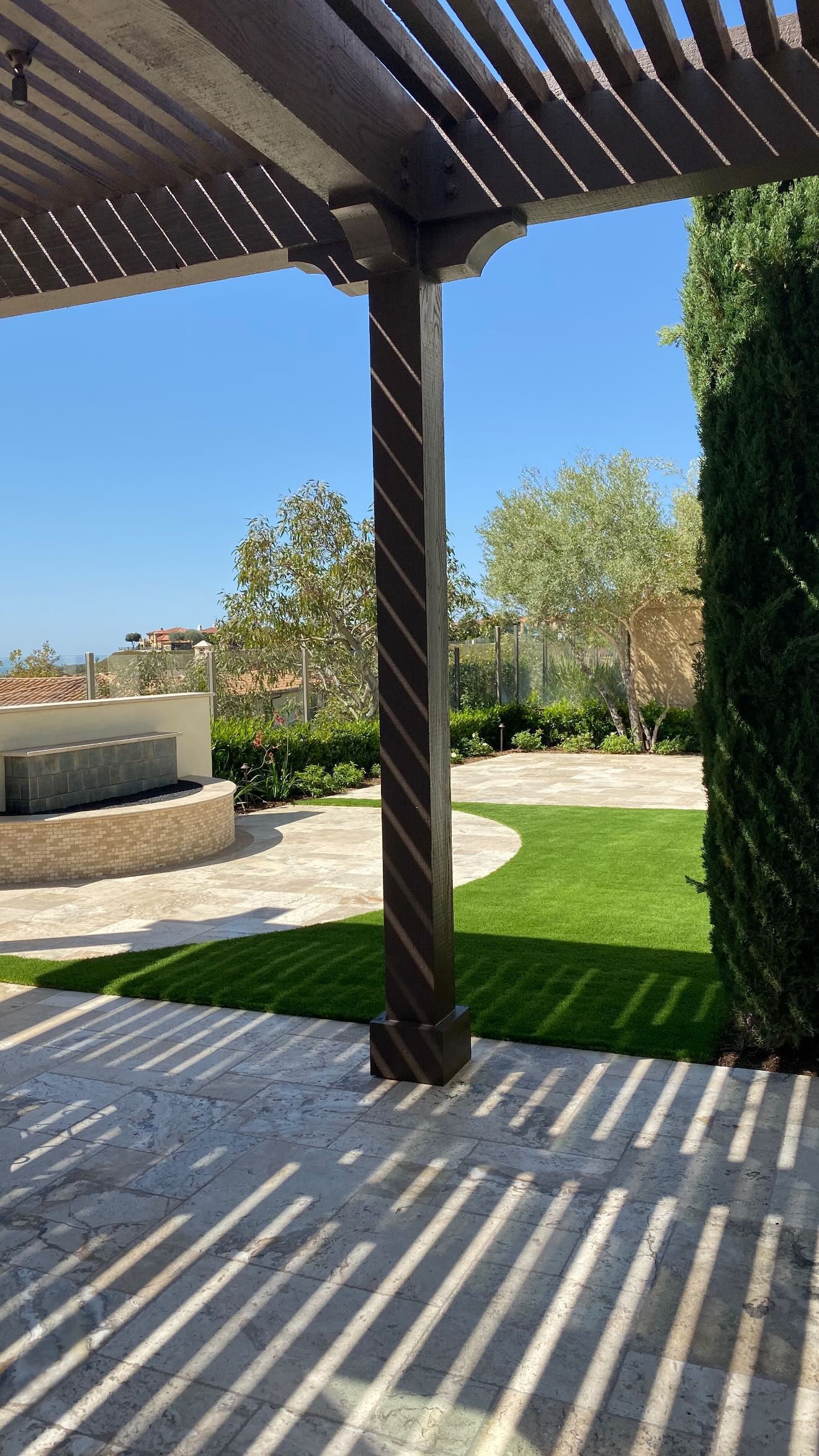 A patio with a pergola overlooking a lush green field.