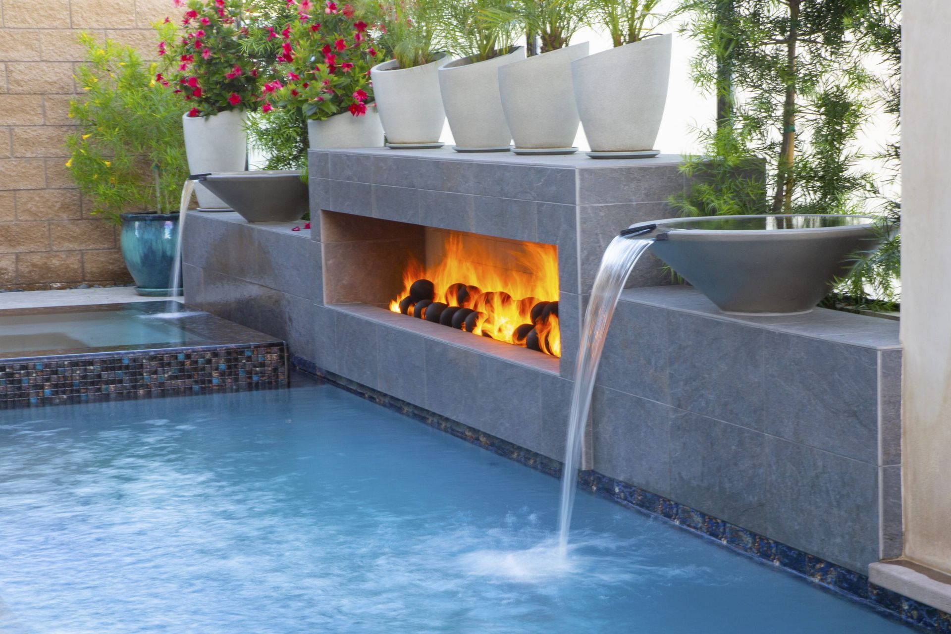 A swimming pool with a fireplace and a waterfall