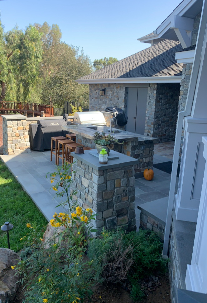 A house with a patio and a grill in the backyard.