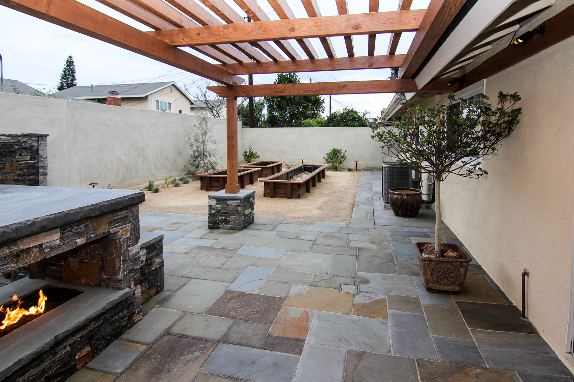 A patio with a fireplace and a wooden pergola
