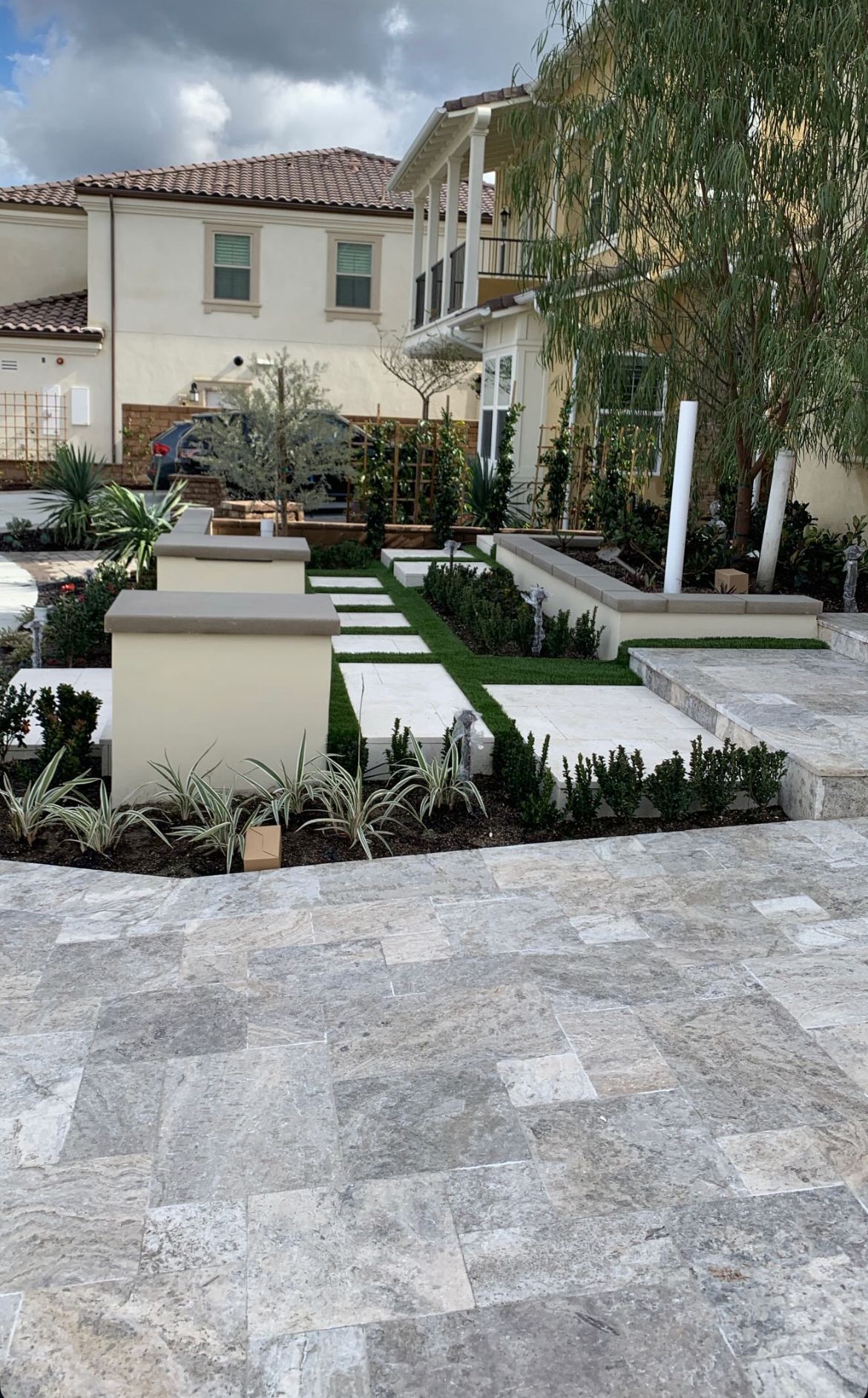 There is a large house in the background and a patio in the foreground.