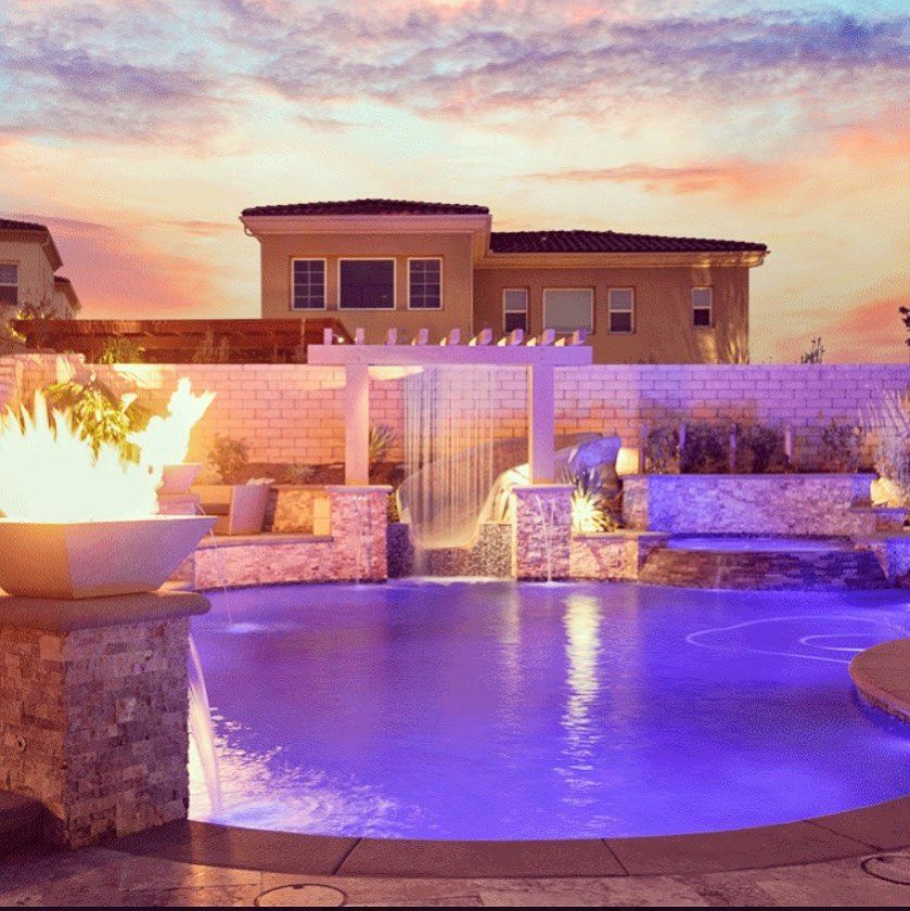 A large swimming pool with a waterfall and a fire pit