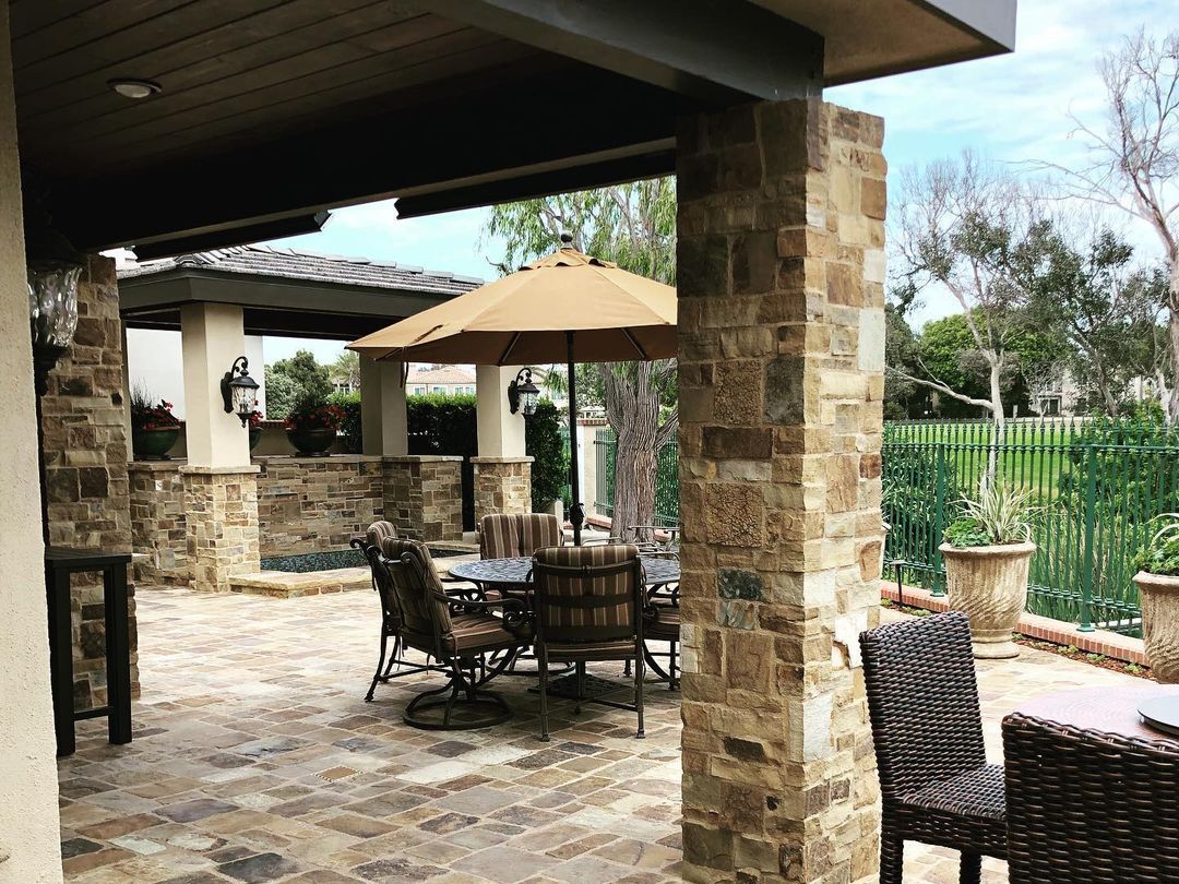 A patio with a table and chairs and umbrellas.