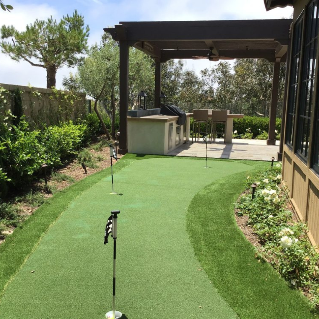 A putting green in front of a house with a pergola
