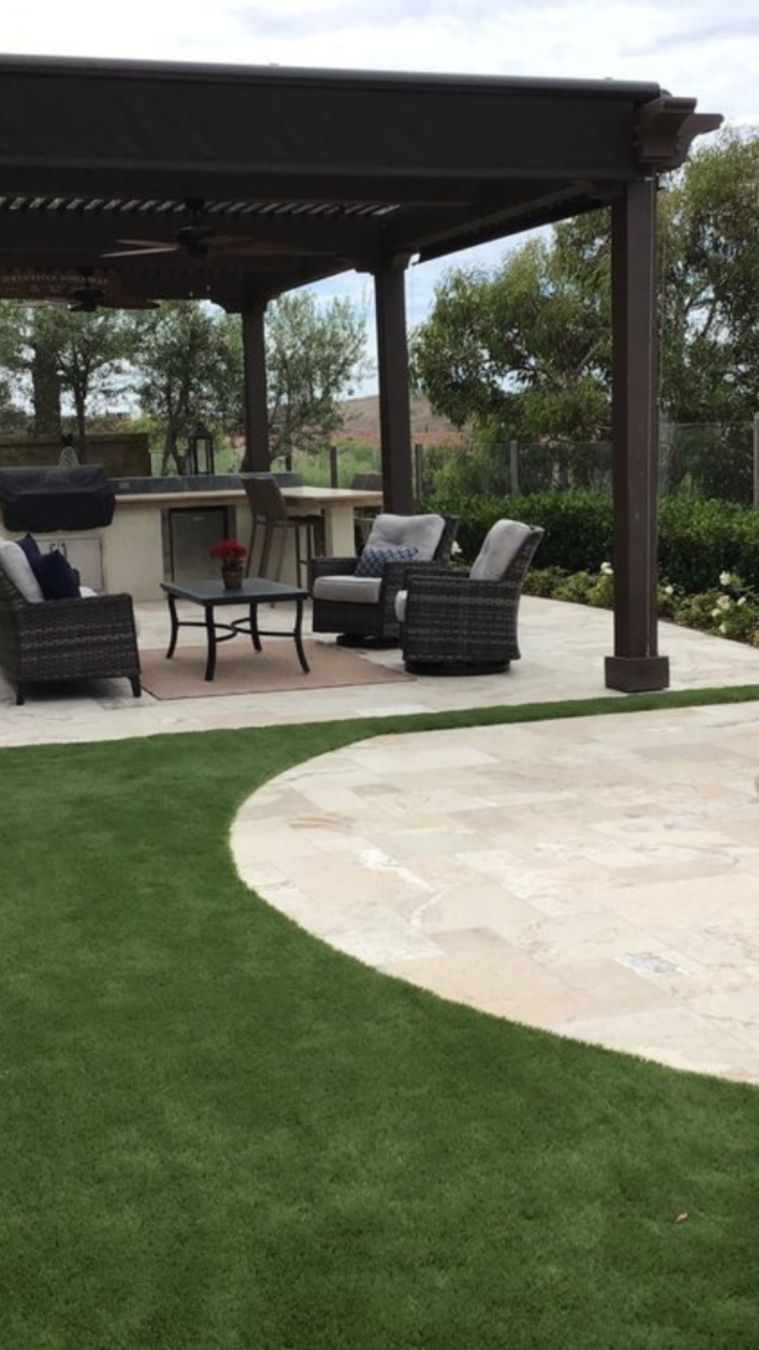 A patio with a pergola , chairs , a table and a grill.