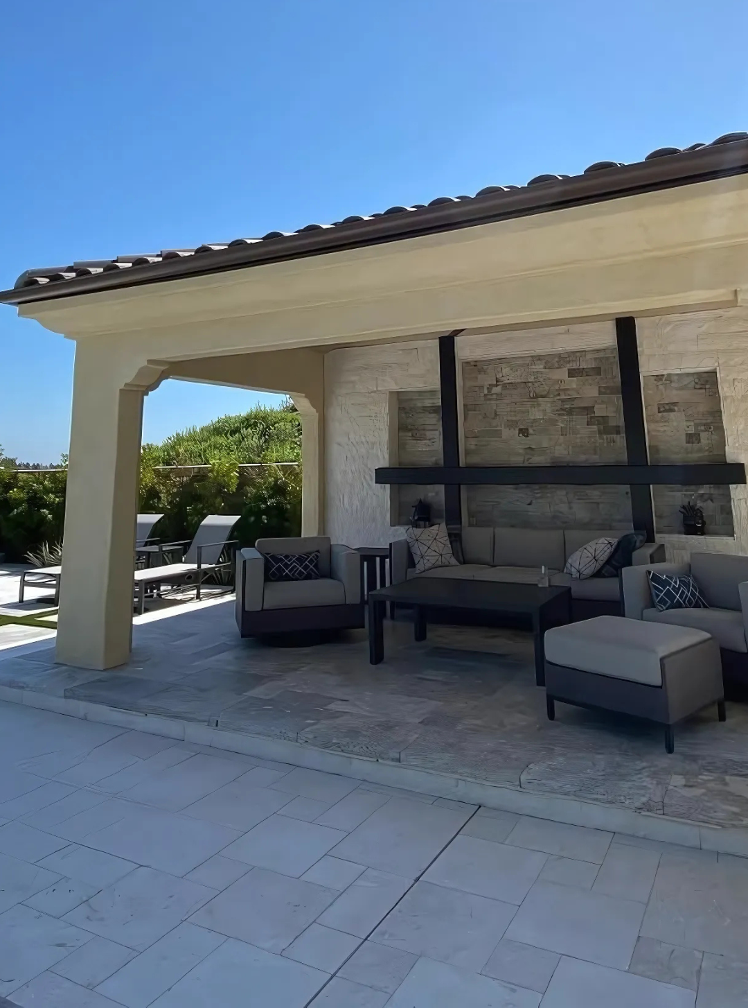 A patio with a couch and chairs under a covered area