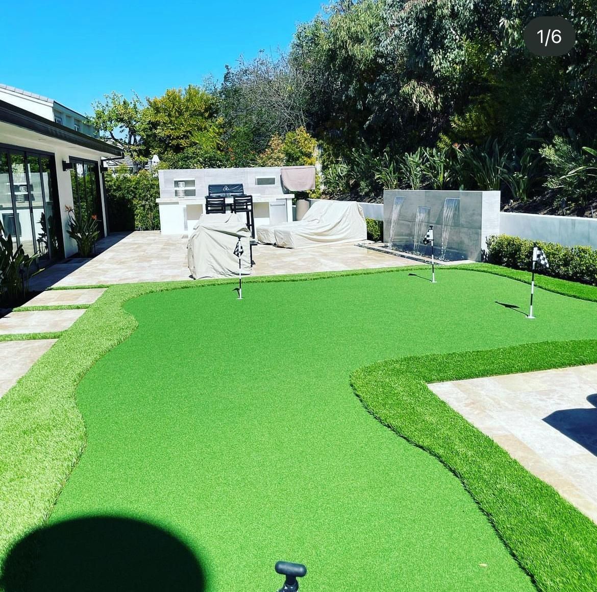 A putting green in front of a house on a sunny day