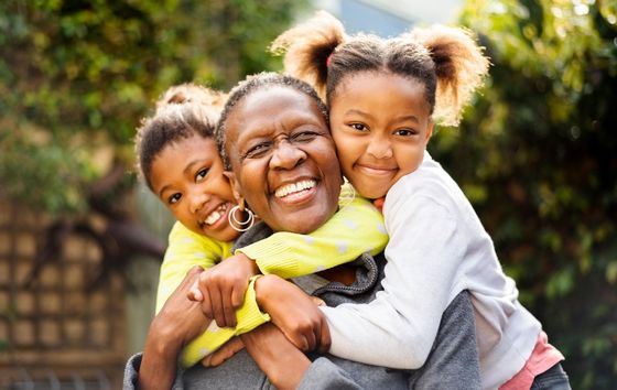 A woman is carrying two little girls on her back.