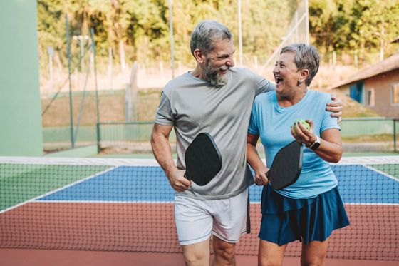 A man and a woman are playing paddle tennis on a tennis court.