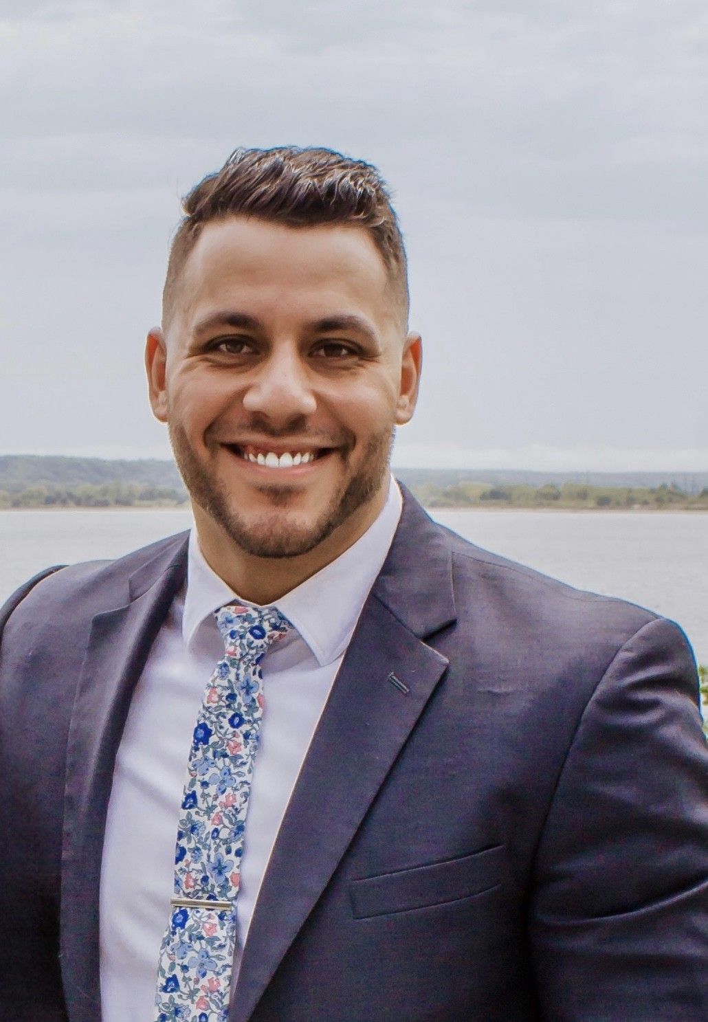 A man with a beard is wearing a suit and smiling