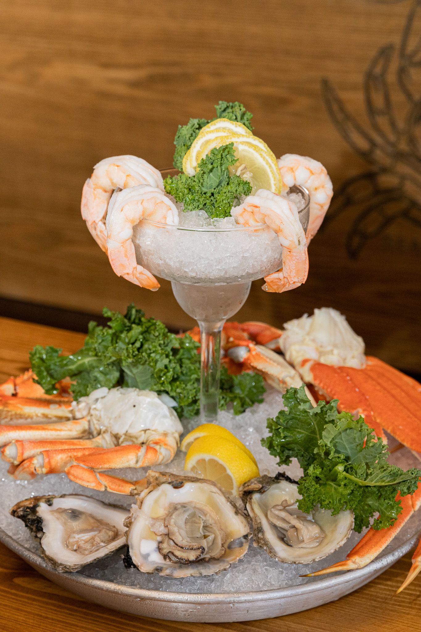 A plate of seafood with shrimp , crab legs , oysters and a martini on ice.