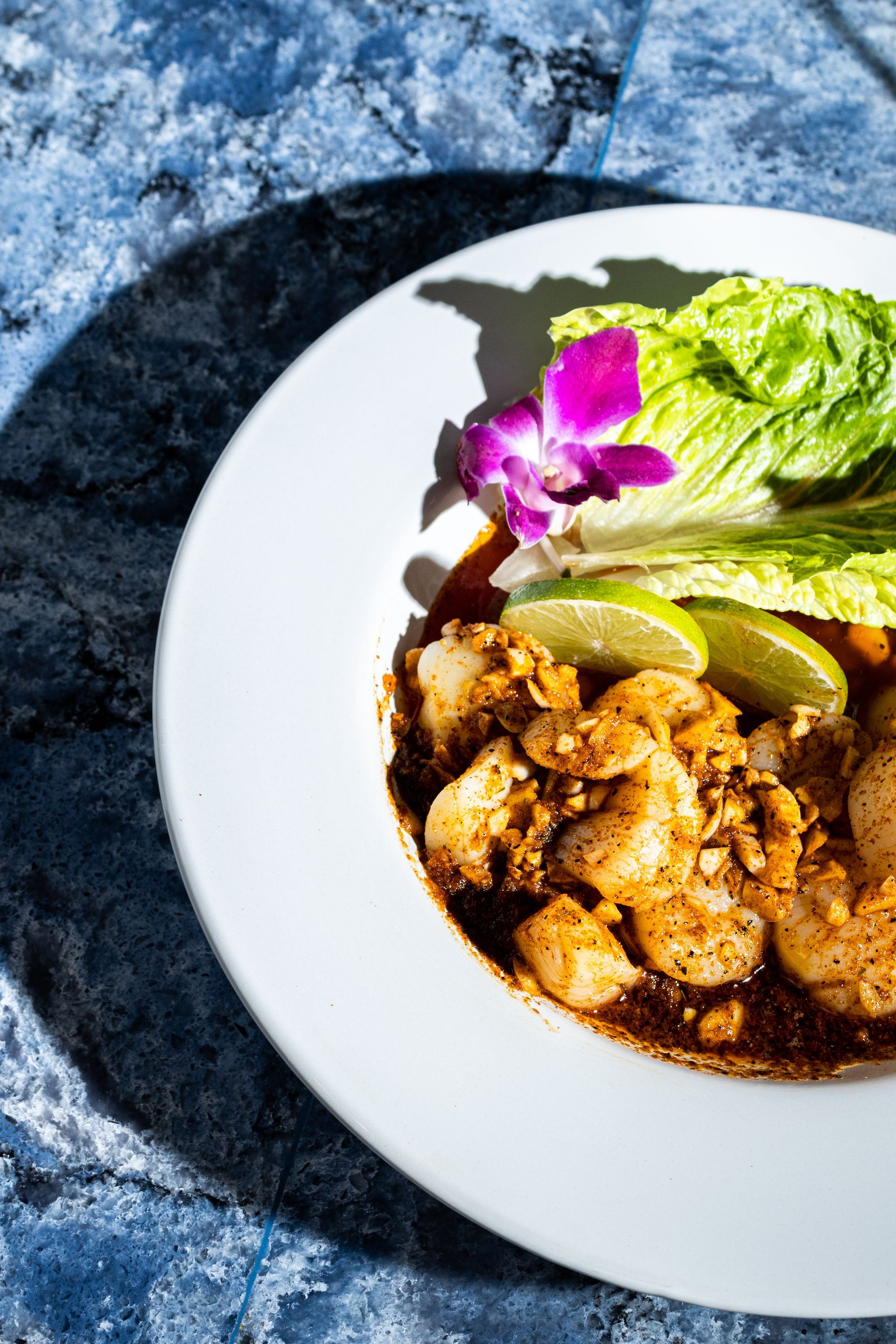 A white plate topped with shrimp and lettuce on a table.