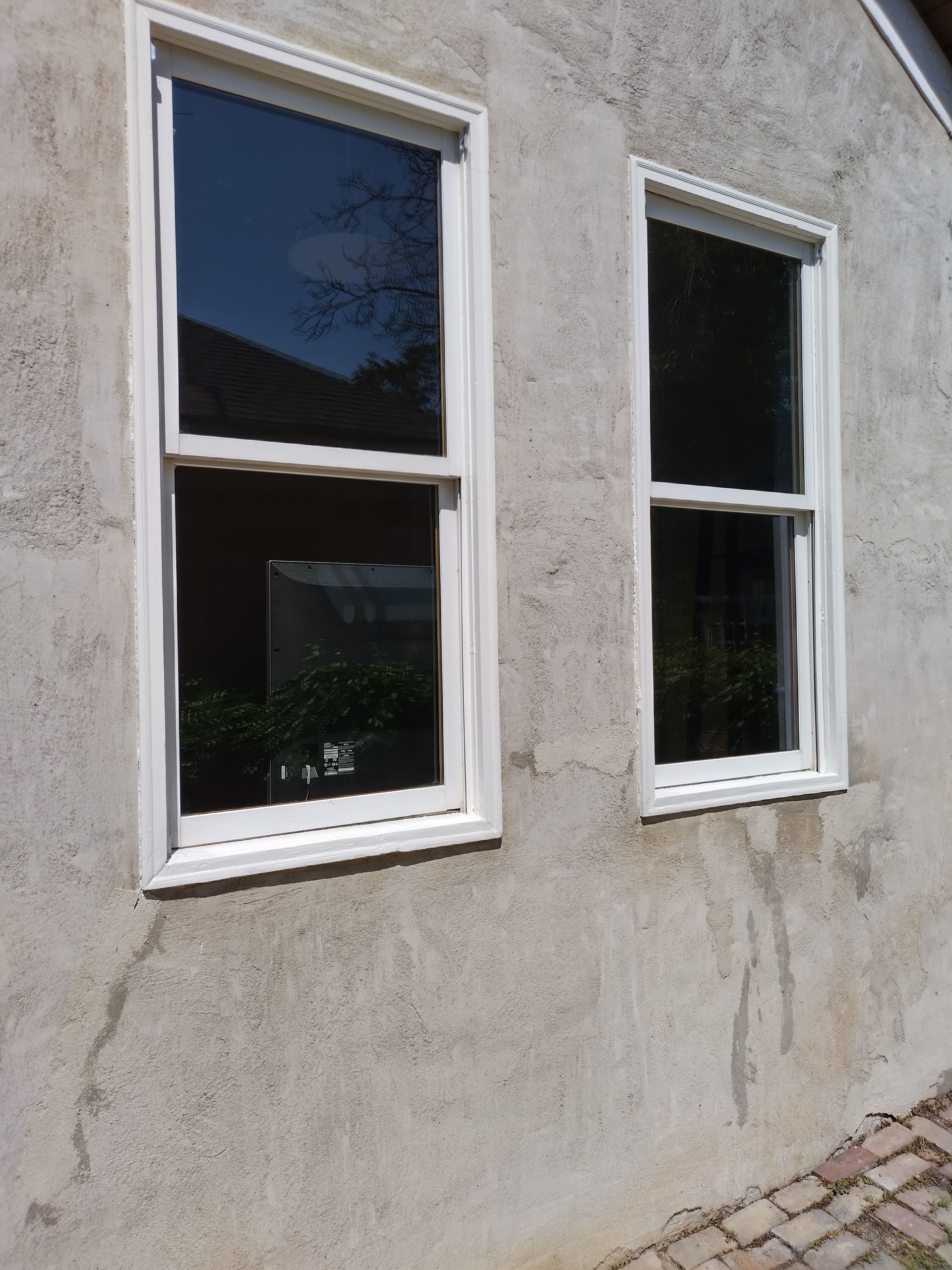 Two windows are on the side of a building