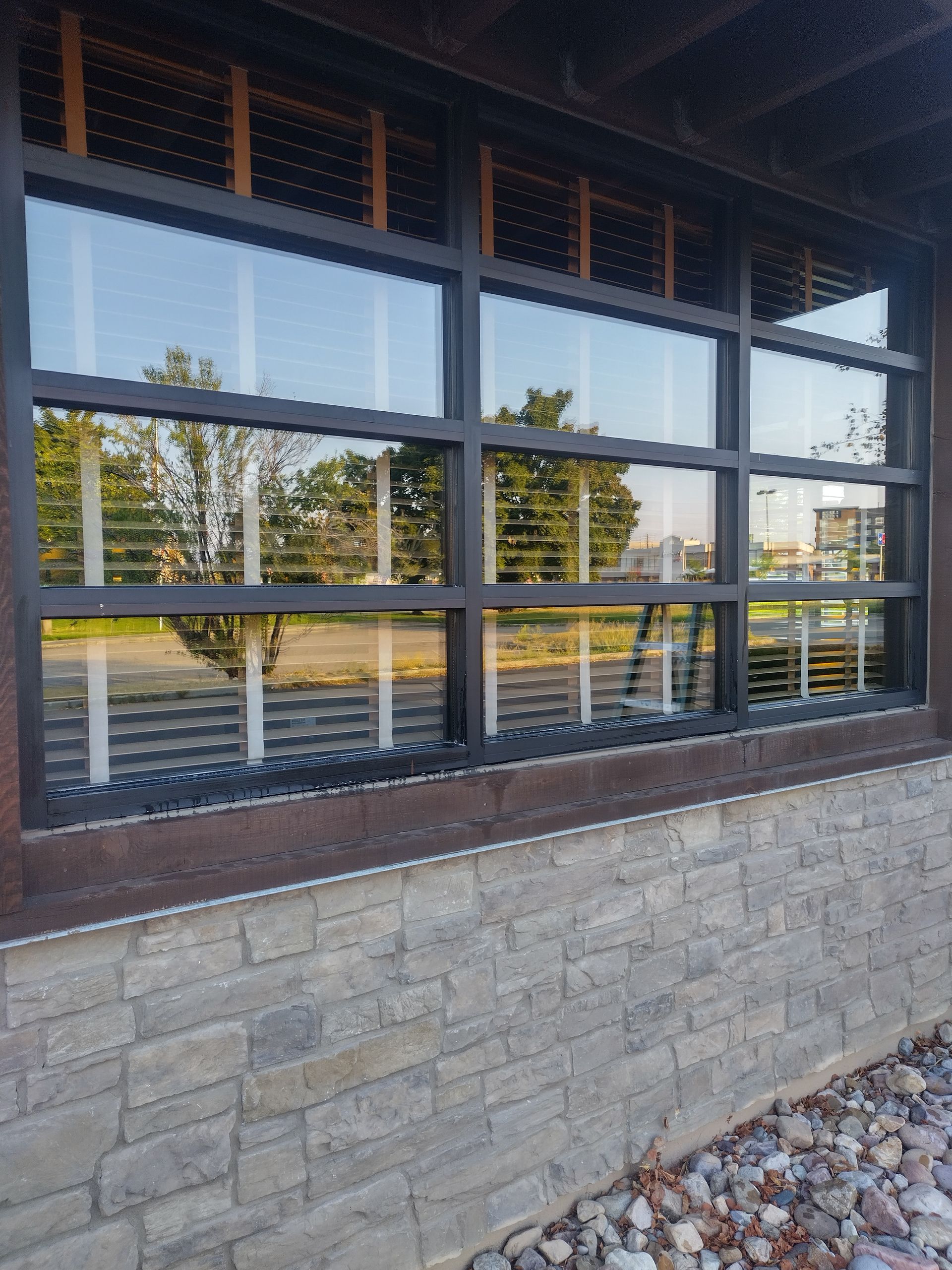 A large window with blinds on it is on a brick wall