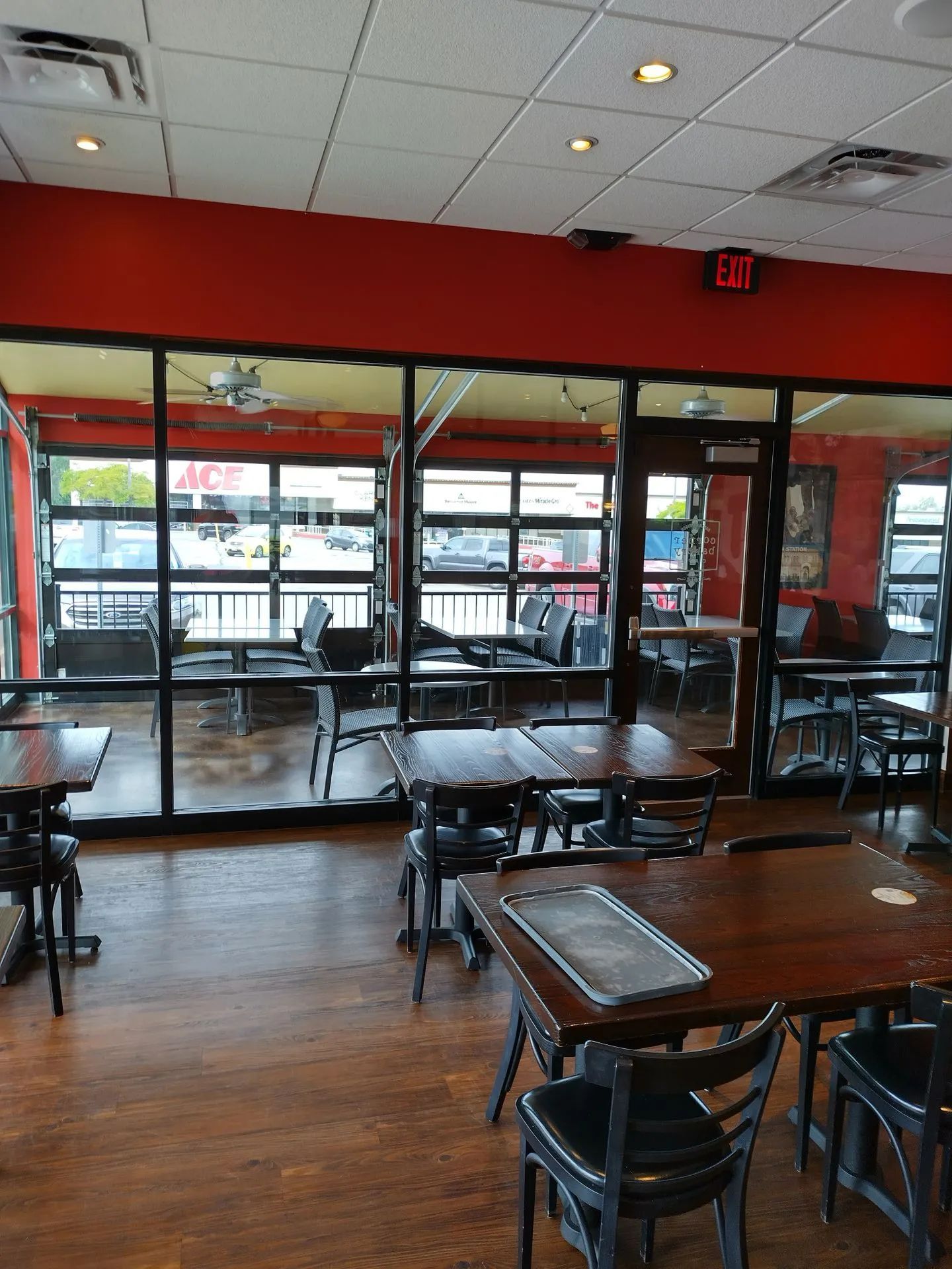 A restaurant with tables and chairs and a red exit sign