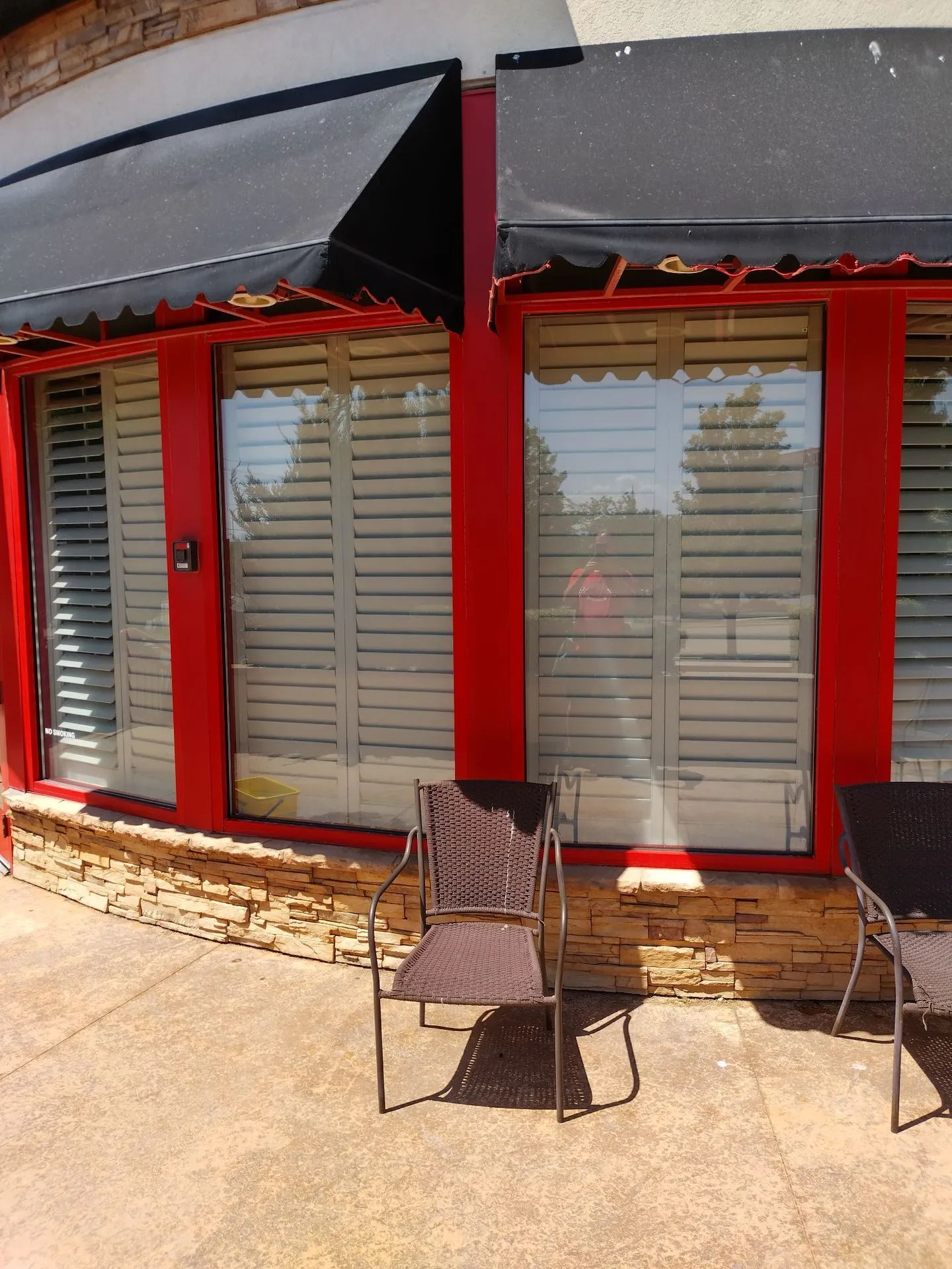 A red building with a black awning and shutters on the windows