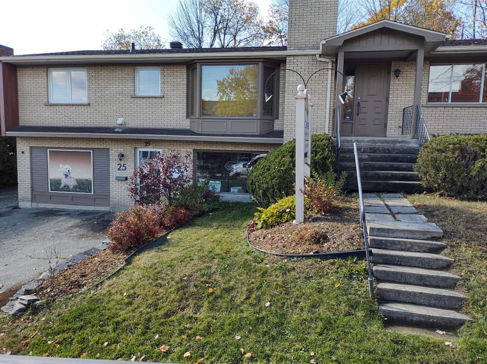 Maison en briques avec un petit porche, des marches et un jardin gazonné.