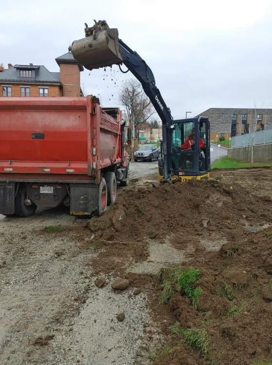 Une excavatrice charge de la terre dans un camion-benne rouge sur un chantier de construction.