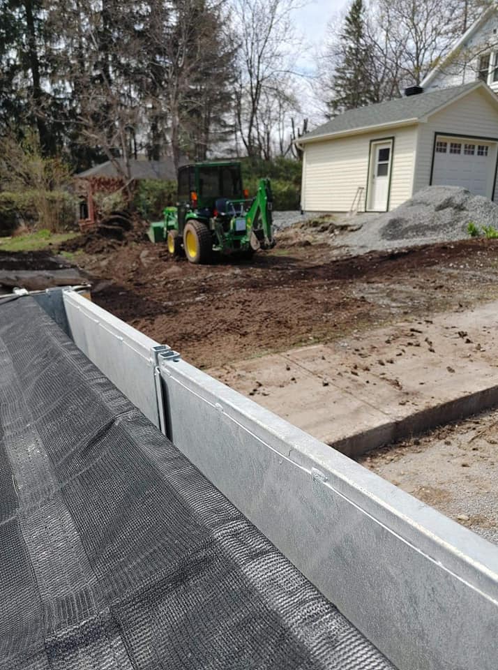 Chantier de construction avec tracteur, mur de soutènement et terre.