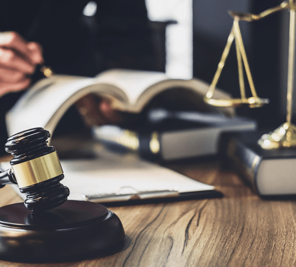 A judge 's gavel is on a wooden table next to a scale of justice