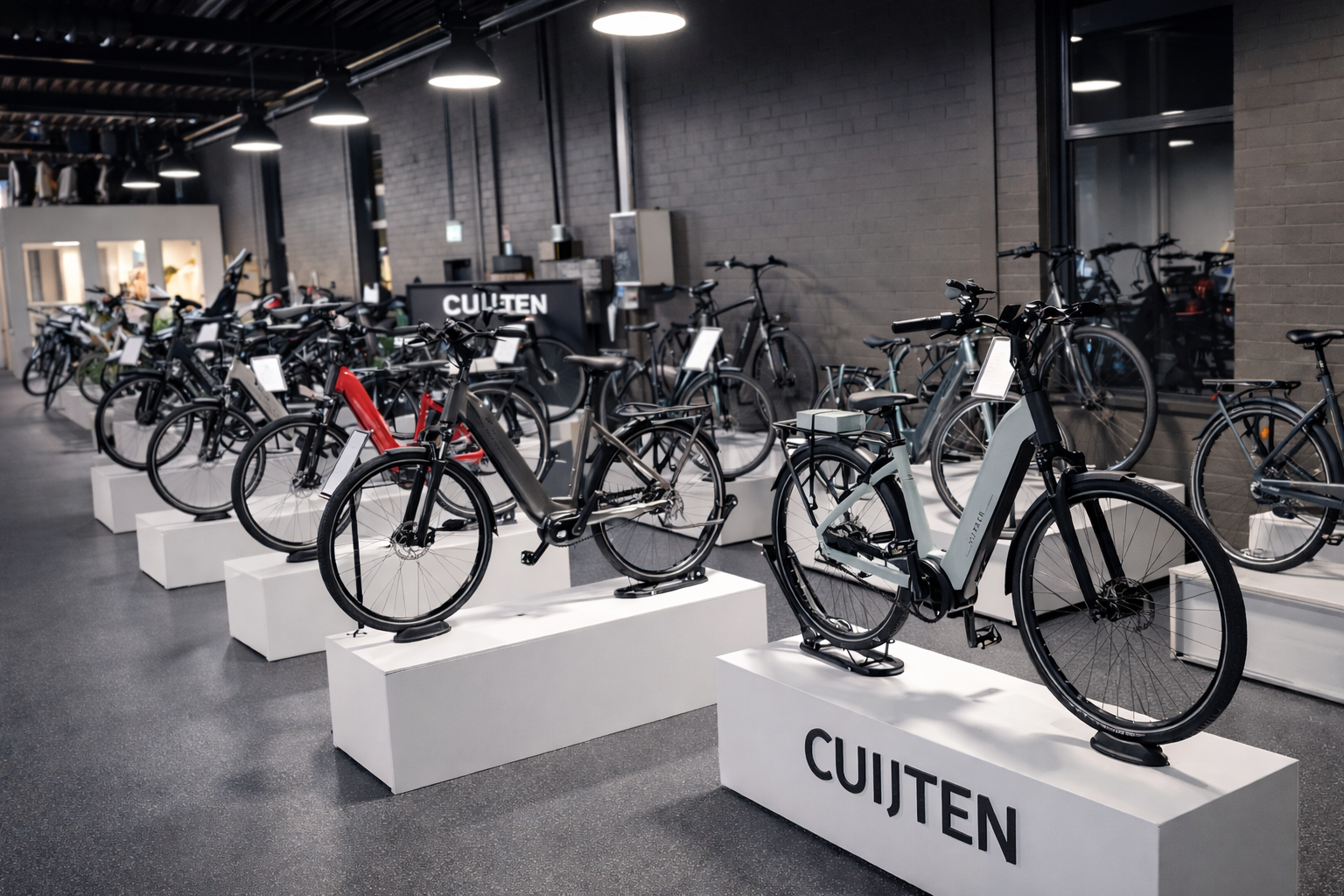 Interieur van een fietsenwinkel met tentoongestelde fietsen, een muur met het logo van de winkel en displayplanken.