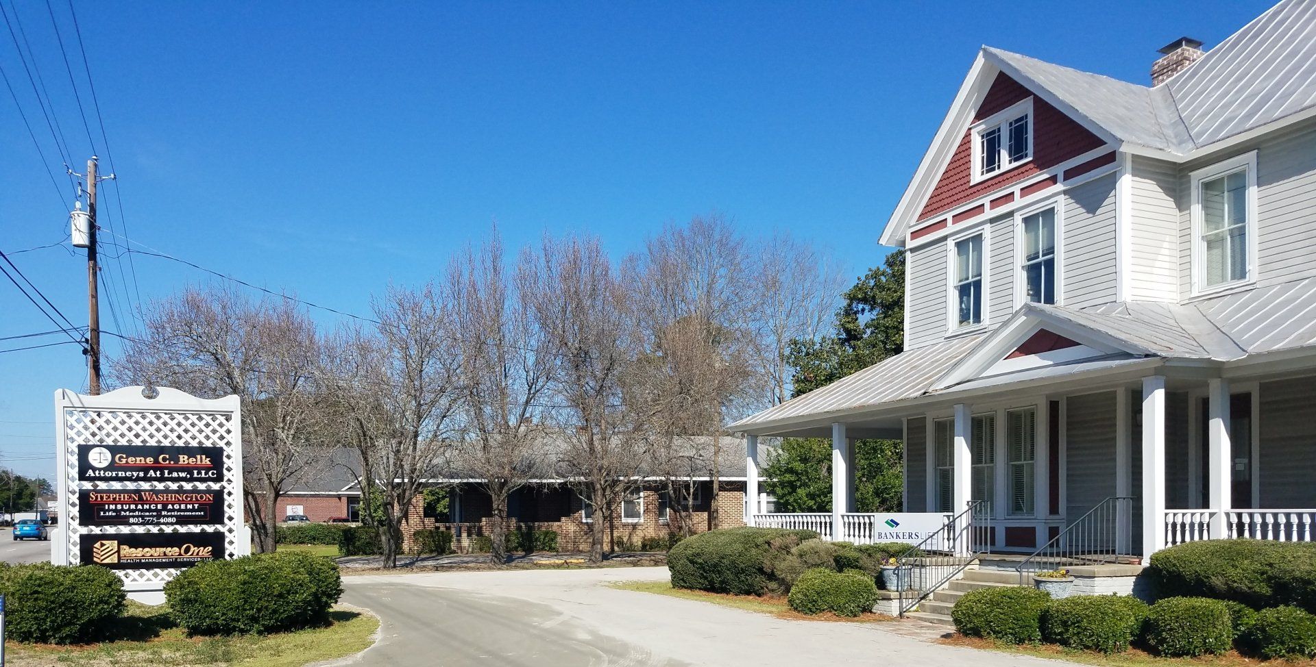 Sign and building with porch on a sunny day. The sign advertises a business.