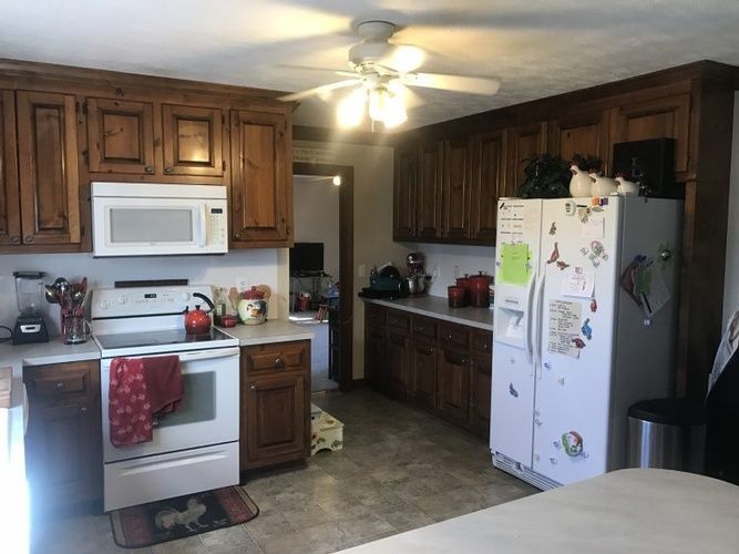 A kitchen with a stove , refrigerator , microwave and ceiling fan.