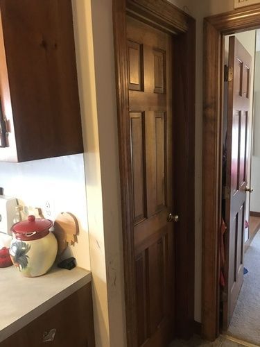 A kitchen with a wooden door and a pot on the counter.