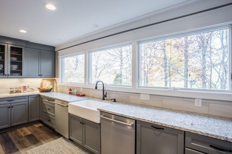 A kitchen with stainless steel appliances , granite counter tops , and a farmhouse sink.