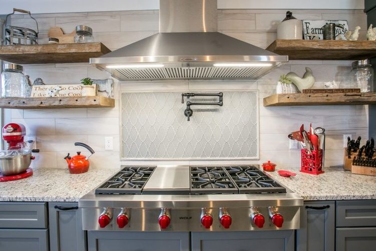A kitchen with a stove top oven and a hood above it.