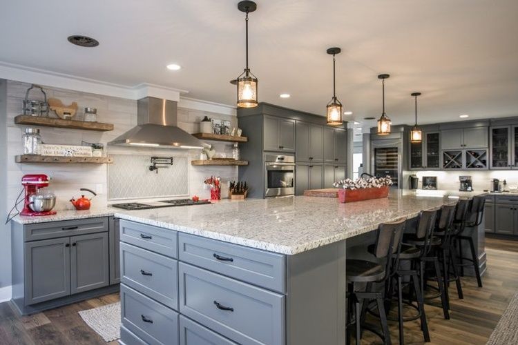 A kitchen with gray cabinets , granite counter tops , stainless steel appliances and a large island.