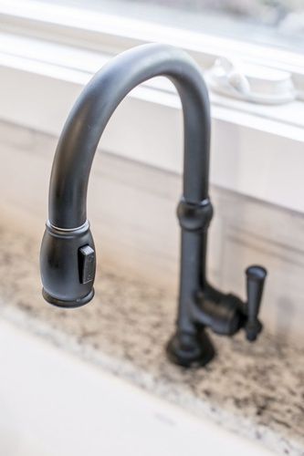 A black kitchen sink faucet is sitting on top of a granite counter.