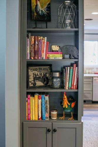 A bookshelf filled with books and chickens in a kitchen.