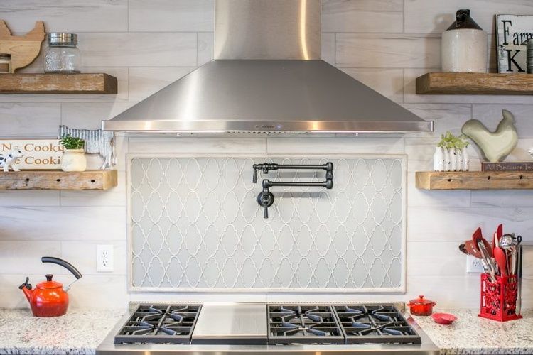 A kitchen with a stove top oven and a stainless steel hood.