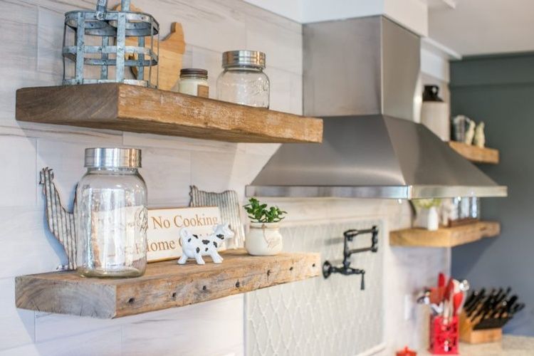 A kitchen with wooden shelves and a stainless steel hood.