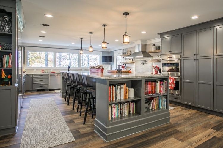 A kitchen with gray cabinets and a large island with bookshelves.