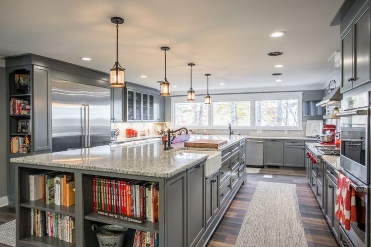 A large kitchen with gray cabinets , granite counter tops , stainless steel appliances , and a large island.