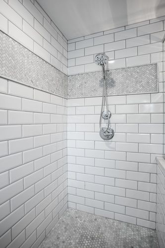 A bathroom with white subway tiles and a walk in shower.