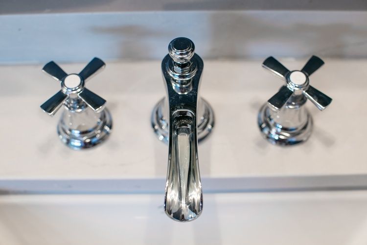 A close up of a bathroom sink faucet with black and white handles